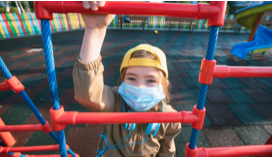 child on playground wearing a mask