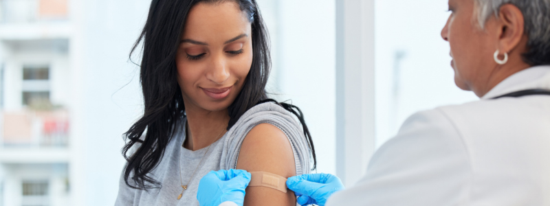 Doctor placing small bandage on patient's arm.